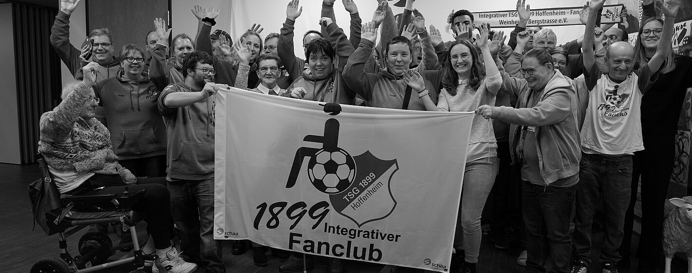 Die Mitglieder des Fanclubs halten mit den Profis zusammen den Banner fest.
